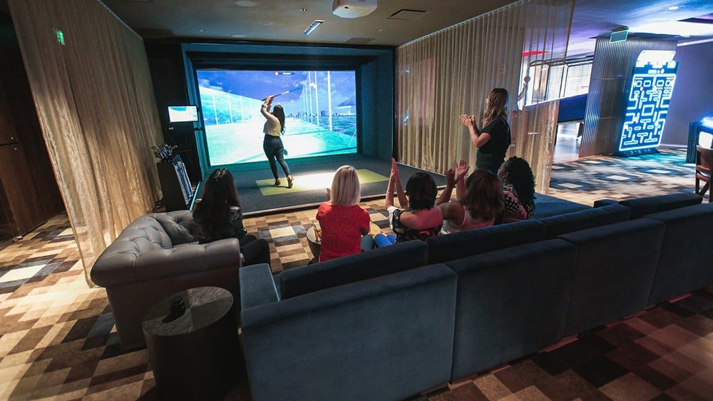 At Topgolf Swing Suite guests hit golf balls at a wall-mounted simulator
